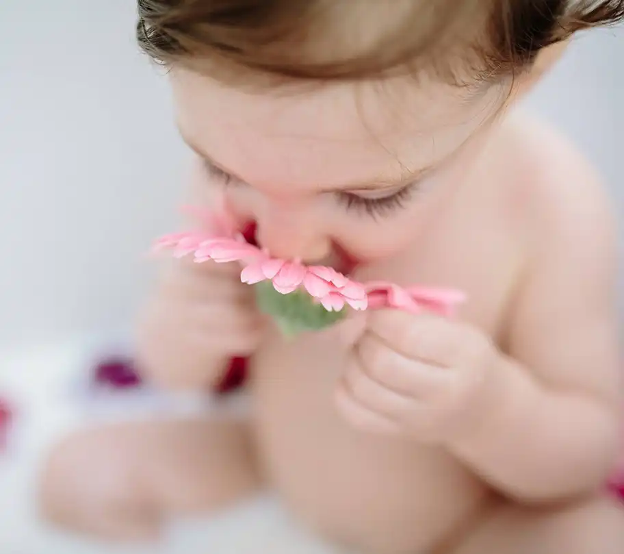 baby smelling a flower