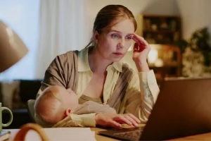 Working mom researching surrogacy agency red flags on a laptop while considering how to become a surrogate.