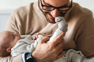 Father holding a newborn baby while exploring whether gestational surrogacy is the right path to parenthood.