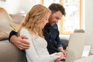 Couple using a laptop to research and compare surrogacy agencies before starting their family-building journey